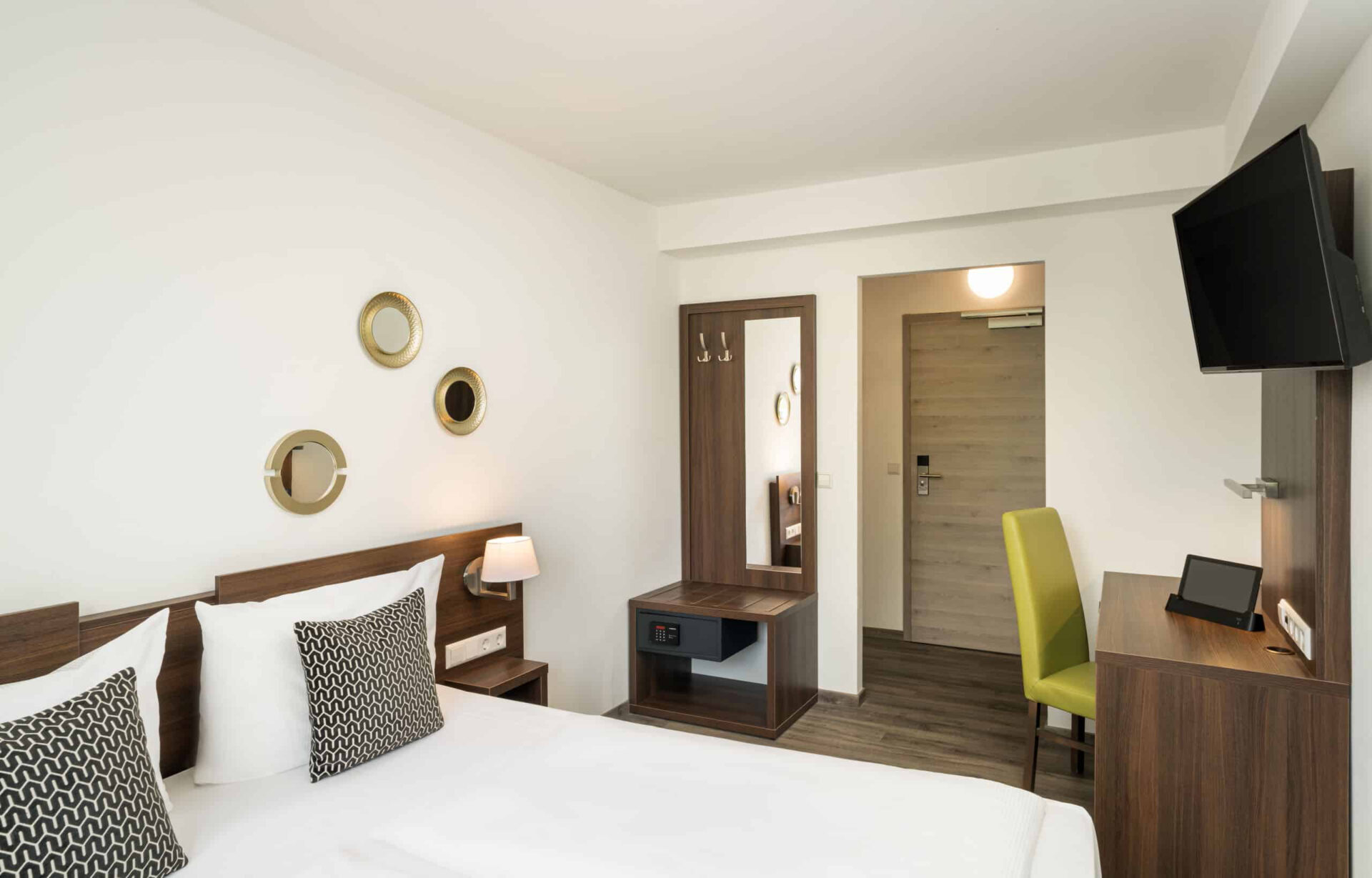 Zimmer mit Sicht auf den Eingangsbereich, Fernseher, das Bett und den Safe im Arthotel ANA Eden