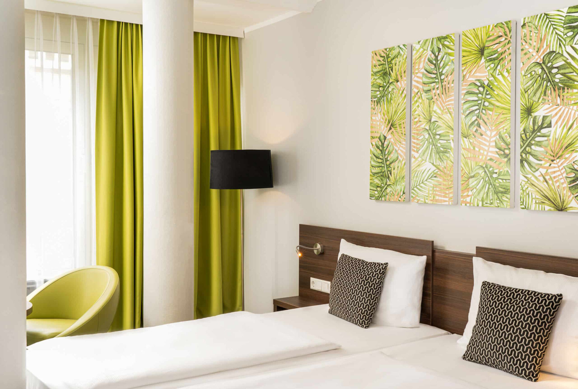 Nahansicht eines Doppelzimmers mit Bett, Vorhängen und Wandbildern im Arthotel ANA Eden