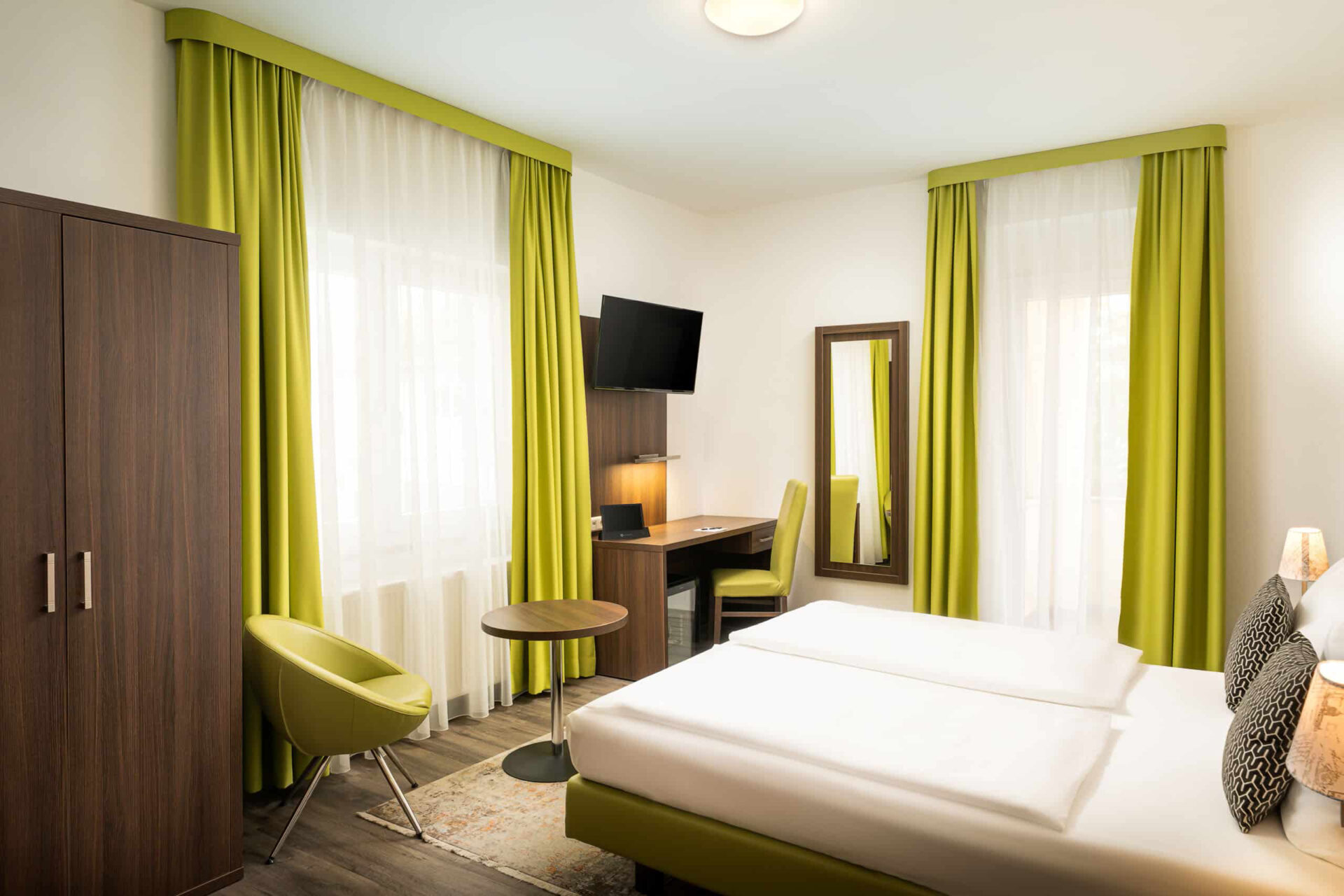 Die seitliche Ansicht eines Doppelzimmers mit Kleiderschrank, Sessel und Schreibtisch im Arthotel ANA Eden