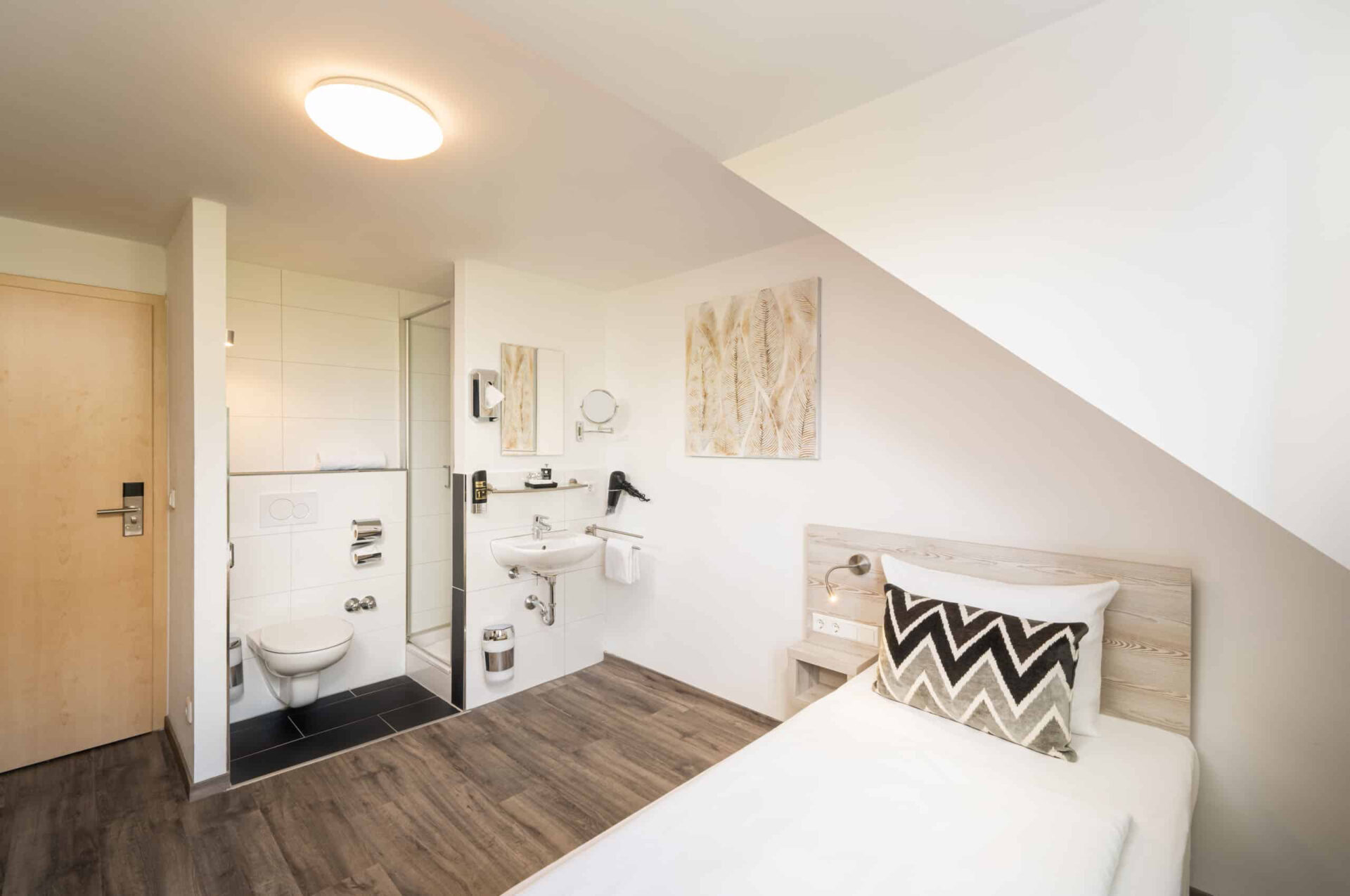 Ein Einzelzimmer mit Bett und Dachschräge im Arthotel ANA Eden