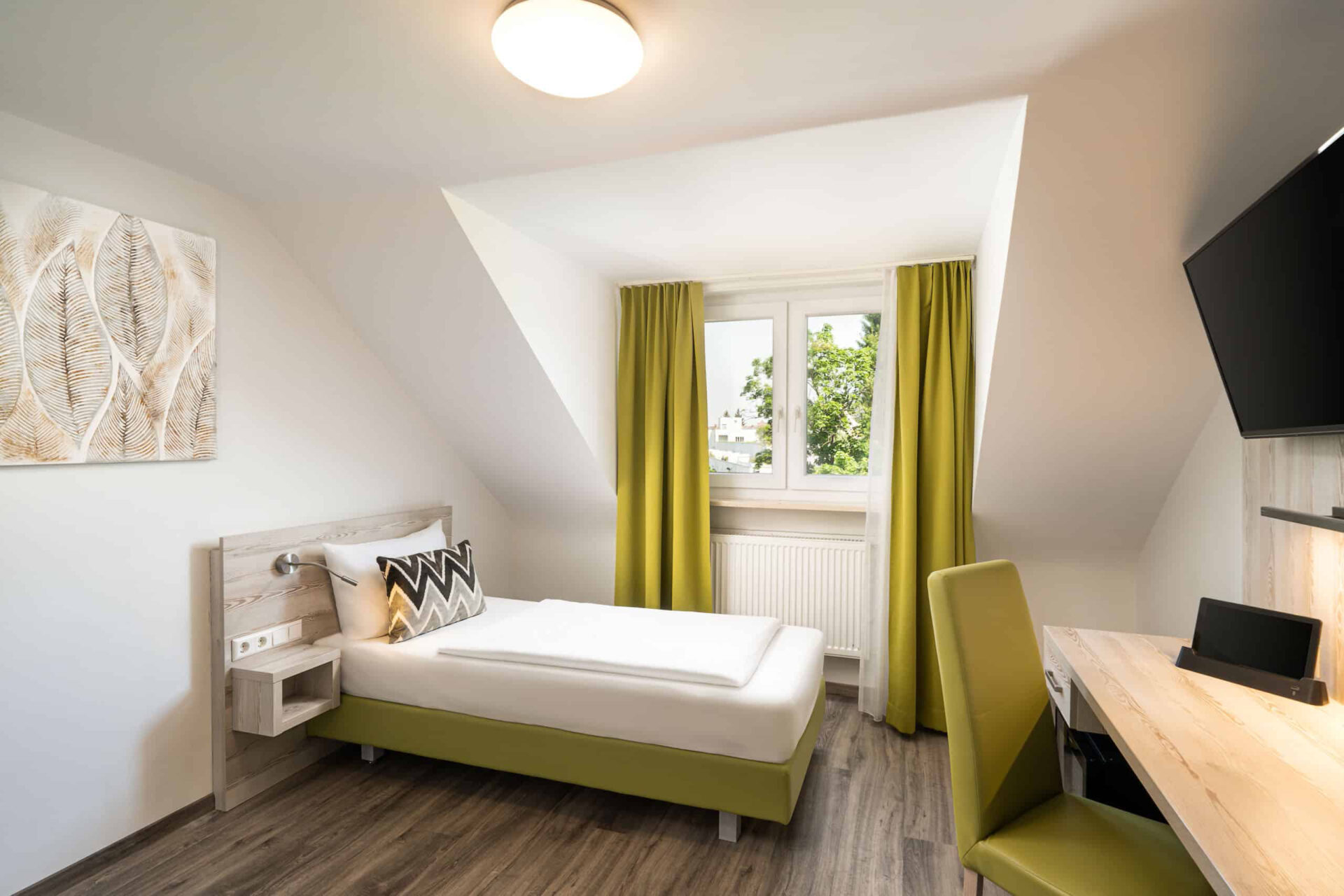 Ein Einzelzimmer mit Bett, Schreibtisch, Lampe, Fernseher und Bett im Arthotel ANA Eden