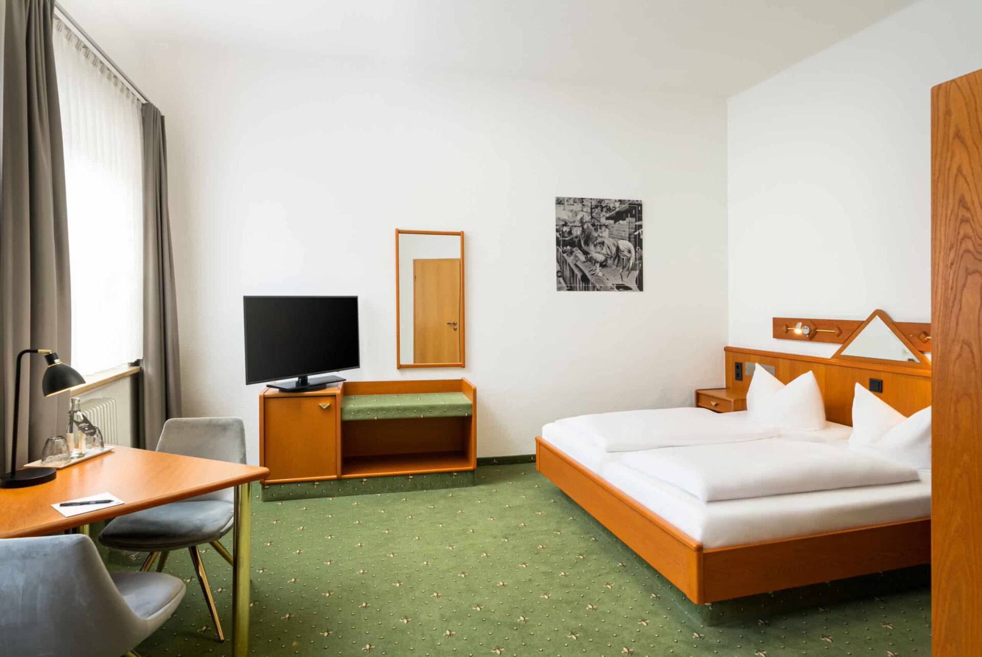 Ein Zimmer mit Doppelbett, Fernseher, Kofferblage und Schreibtisch im Arthotel ANA Goggl