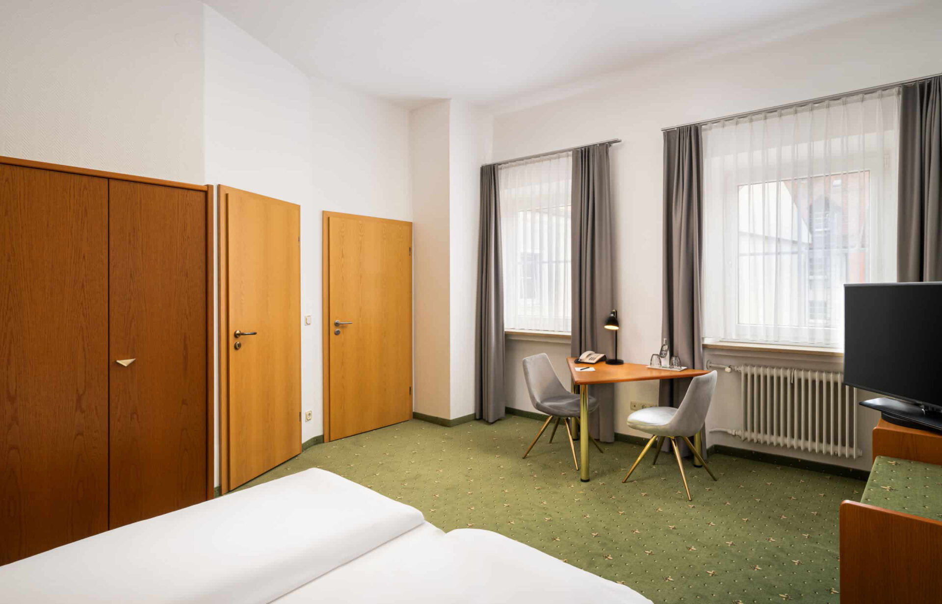 Der Schreibtisch, Kleiderschrank und Fernseher eines Zimmers im Arthotel ANA Goggl