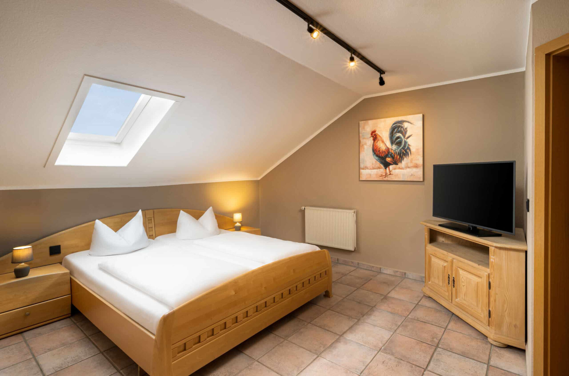 Ein Doppelzimmer mit Bett, Fernseher und Dachschräge im Arthotel ANA Goggl