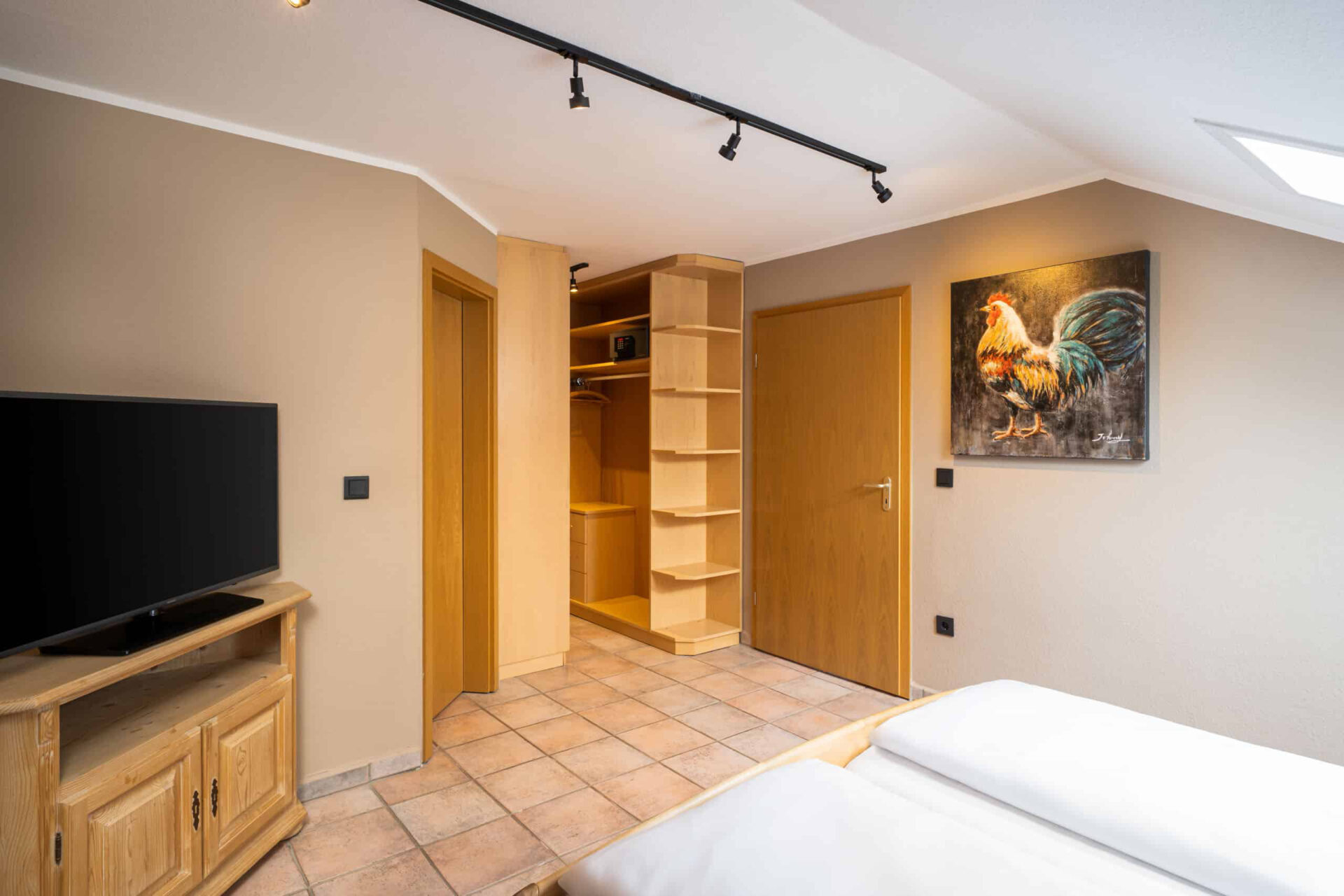 Ein Zimmer mit Kleiderschrank, Fernseher und Wandbild im Arthotel ANA Goggl
