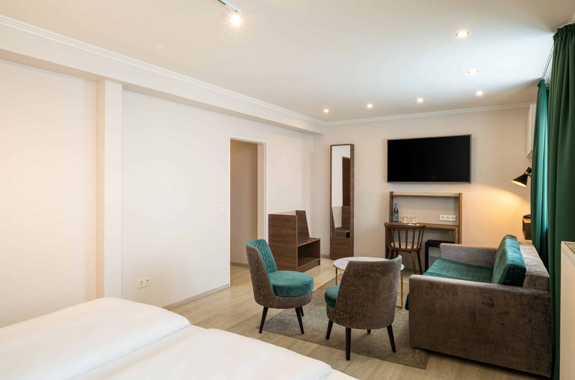 Die Sitzecke eines Dreibettzimmers mit Fernseher im Arthotel ANA Liberty Bremen