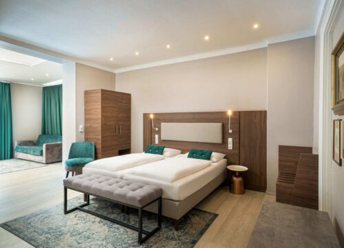 Das Doppelbett der Juniorsuite mit Nachttisch, Sessel und Kofferablage im Arthotel ANA Liberty Bremen