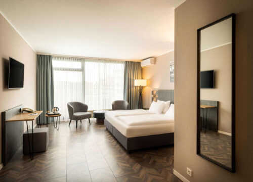 Das Superior Doppelzimmer mit Spiegel, Doppelbett und Sitzgelegenheiten im Arthotel ANA Neotel Stuttgart