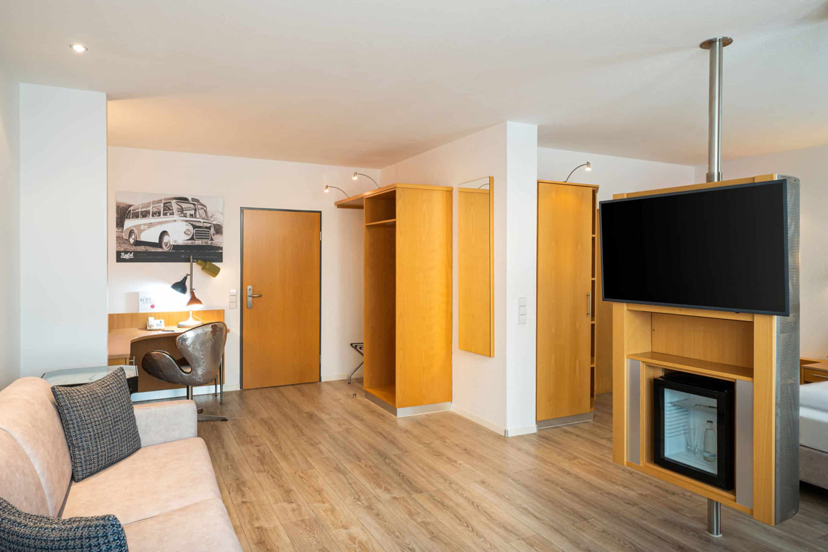 Das Sofa, der Schreibtisch und ein Kühlschrank eines Zimmers im Arthotel ANA Neotel Stuttgart