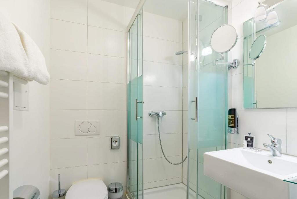 Ein helles Badezimmer mit Spiegeln, Toilette und einer Dusche im Arthotel ANA Style