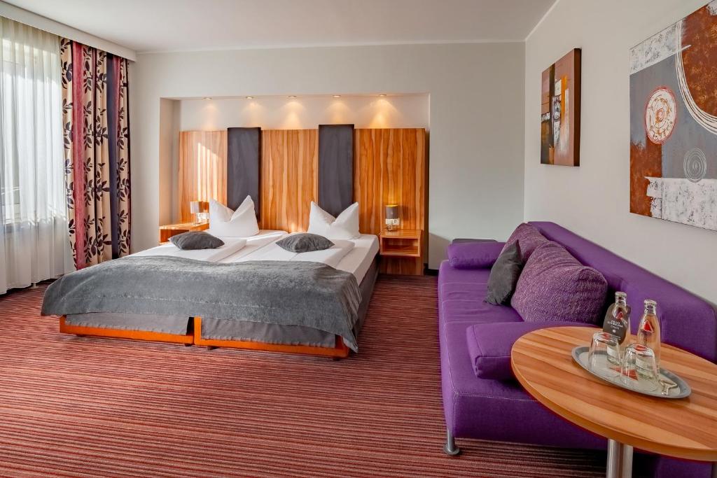 Ein Doppelzimmer mit großem Sofa, Beistelltisch und Bett im Arthotel ANA Style