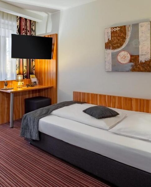 Ein Einzelzimmer mit Fernseher, Schreibtisch und Lampe im Arthotel ANA Style