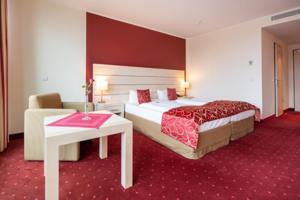 Das Doppelbett , der Sessel sowie Beistelltisch eines Zimmers im Aspire Acara Oldenburg