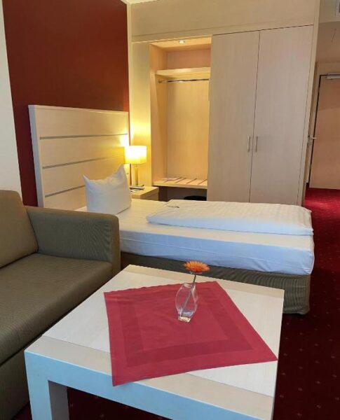 Der Beistelltisch und das Bett eines Zimmers im Aspire Acara Oldenburg