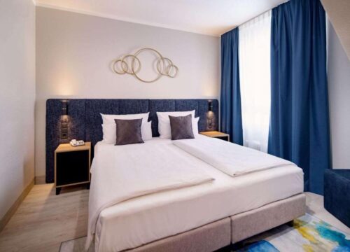 Ein Doppelzimmer mit Sicht auf das Fenster mit Vorhängen im Aspire Elements Reutlingen