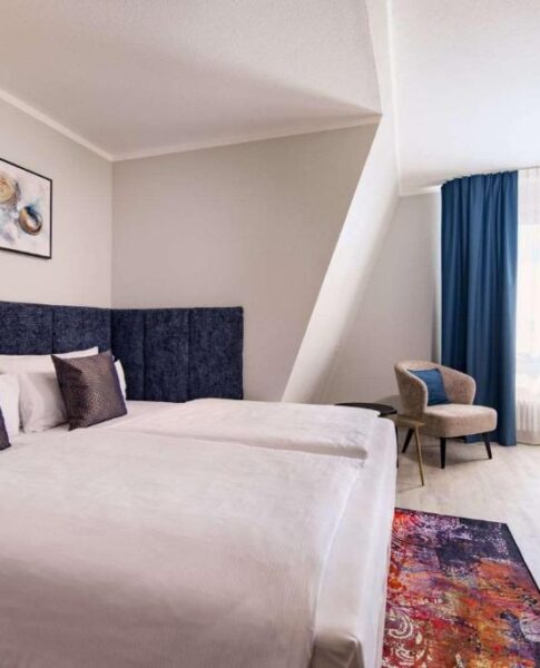 Ein Doppelzimmer mit Doppelbett, Sessel und Schreibtisch im Aspire Elements Reutlingen