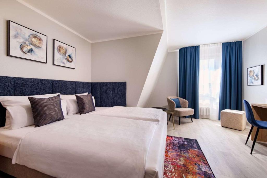 Ein Doppelzimmer mit Doppelbett, Sessel und Schreibtisch im Aspire Elements Reutlingen