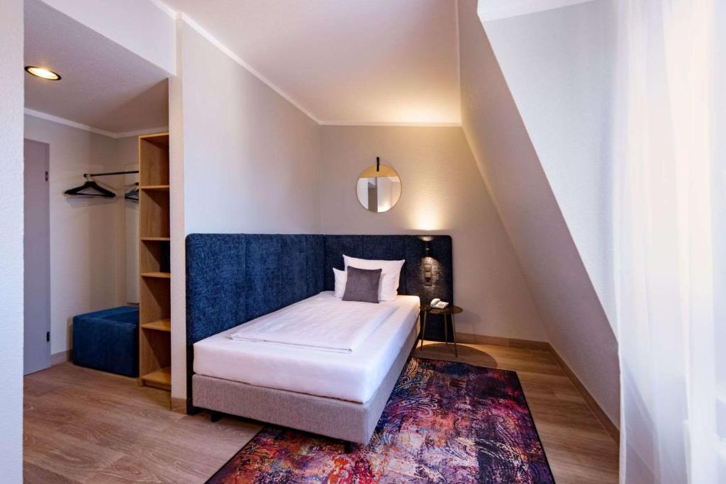 Ein Einzelzimmer mit Bett, Kleiderstange und Stauraum im Aspire Elements Reutlingen