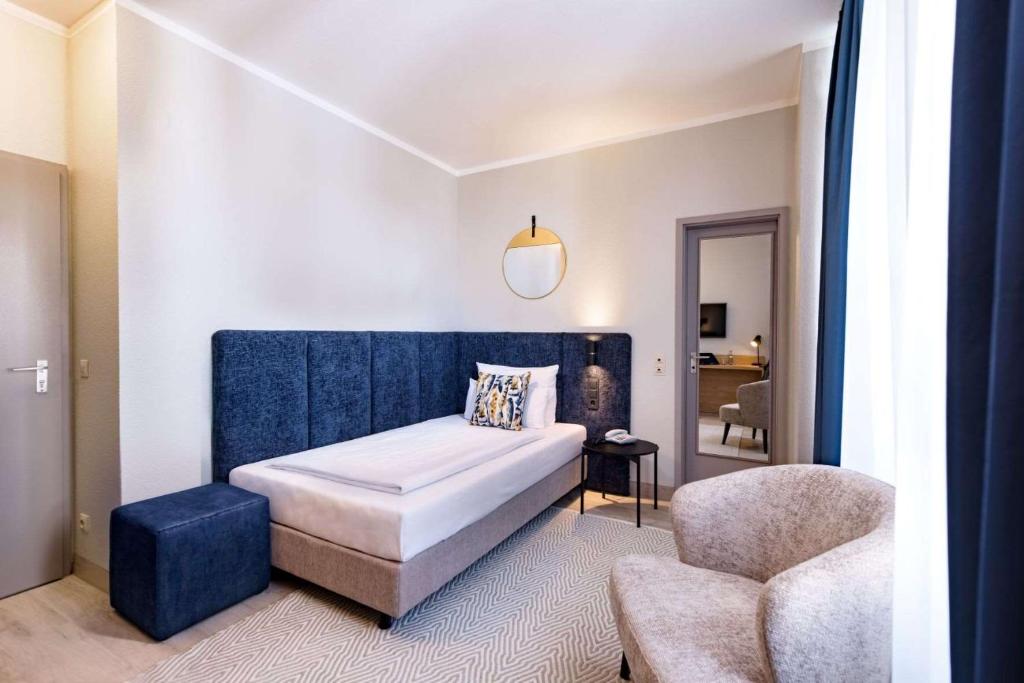 Das Bett, der Sessel und der Spiegel eines Einzelzimmers im Aspire Elements Reutlingen