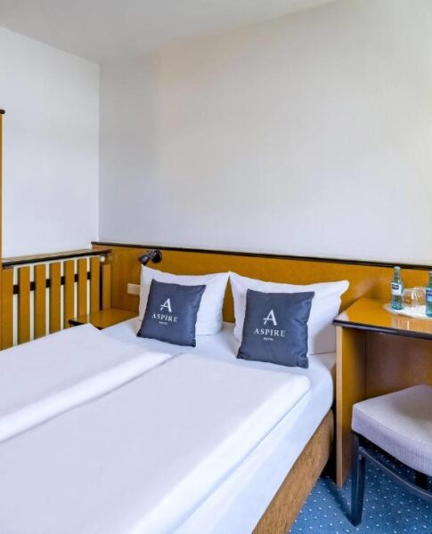 Ein Doppelzimmer mit Doppelbett und Schreibtisch im Aspire Frankfurt Airport