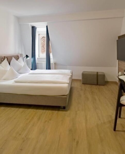 Ein Doppelzimmer mit Fenster, Fernseher, Schreibtisch und Sessel im Aspire Kronprinz