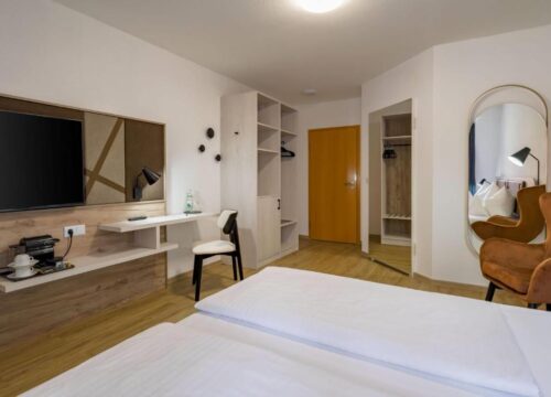 Ein Doppelzimmer mit Fernseher und Spiegel im Aspire Kronprinz