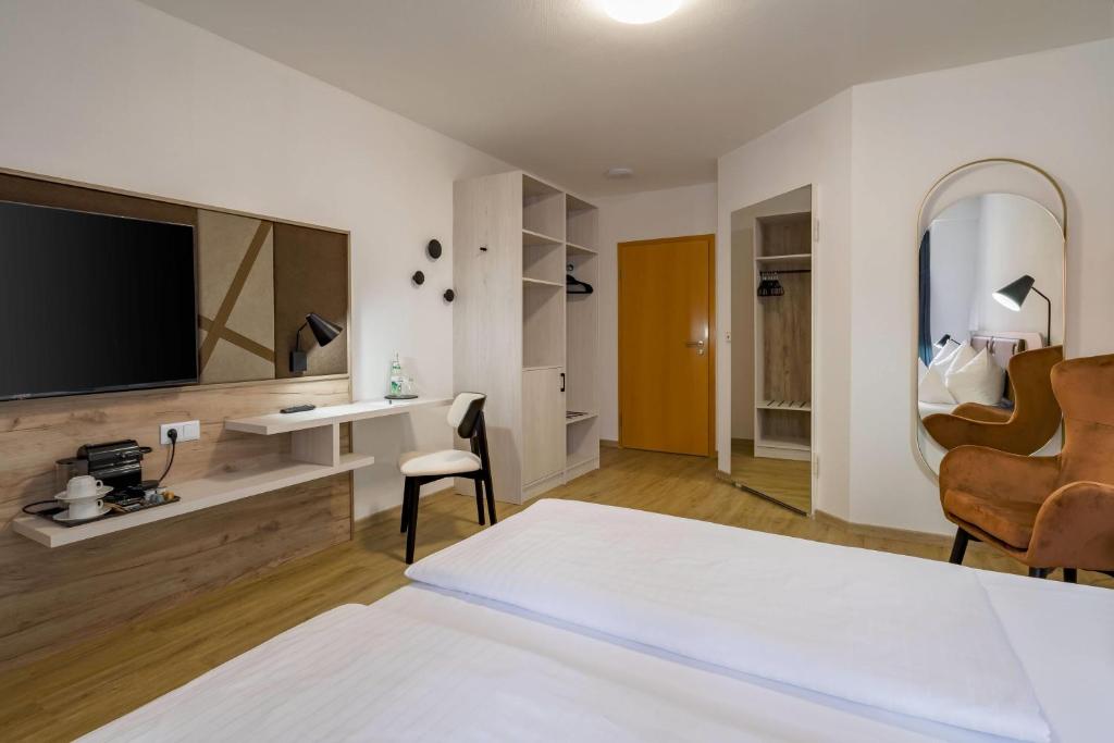 Ein Doppelzimmer mit Fernseher und Spiegel im Aspire Kronprinz 