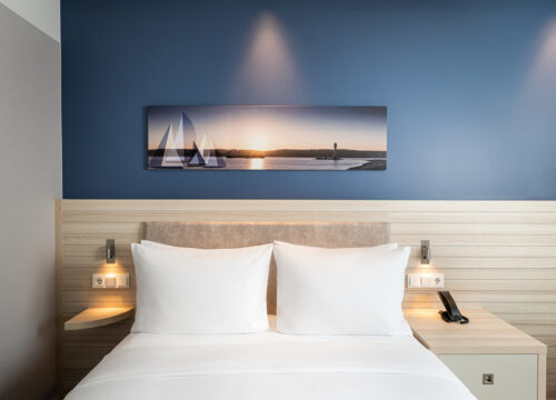 Das Bett mit Portrait und Nachttischlampen im Hampton by Hilton Kiel