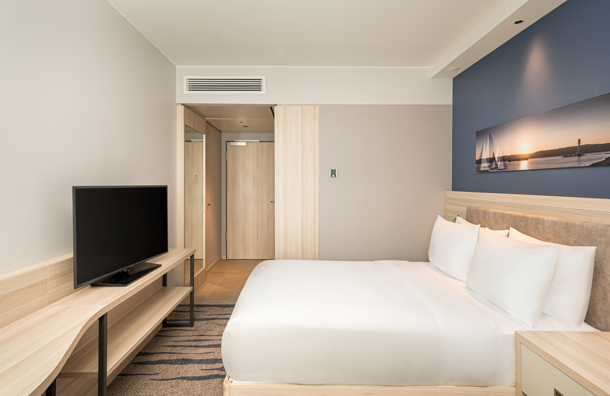 Der Fernseher, das Bett und der Spiegel eines Zimmers im Hampton by Hilton Kiel