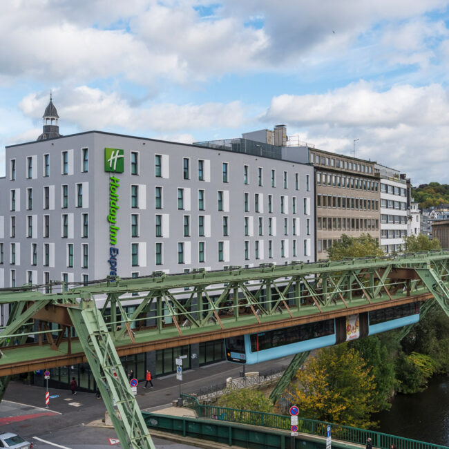 Außenansicht des Holiday Inn Express Wuppertal mit Sicht auf die Schwebebahn