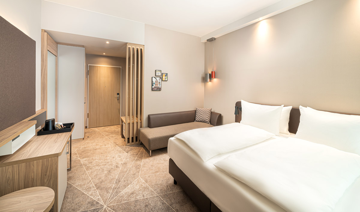 Ein Doppelzimmer mit Fernseher und Sofa, sowie einem Wasserkocher im Holiday Inn Mannheim