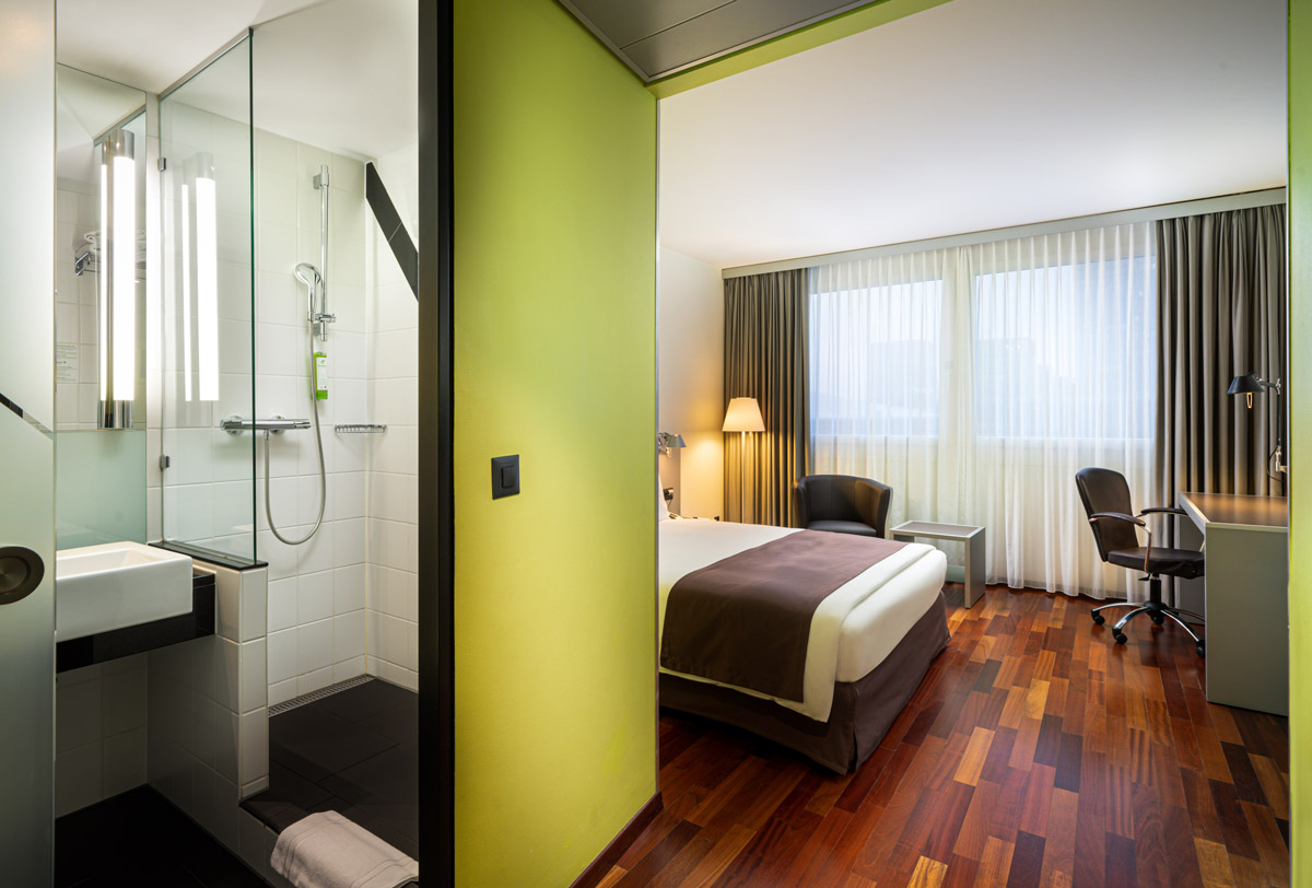 Das Badezimmer und der Schlafbereich eines Einzelzimmers im Holiday Inn Zürich Messe