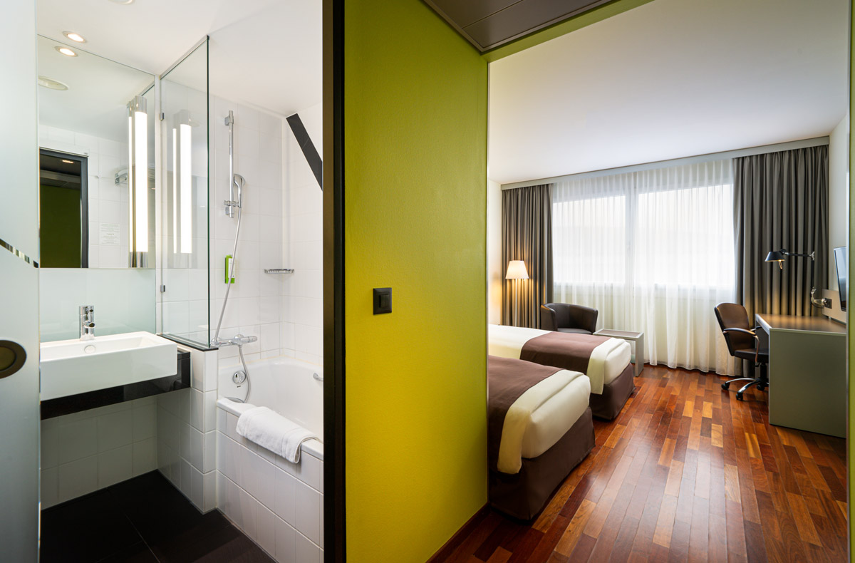 Das Badezimmer und der Schlafbereich eines Zimmers im Holiday Inn Zürich Messe