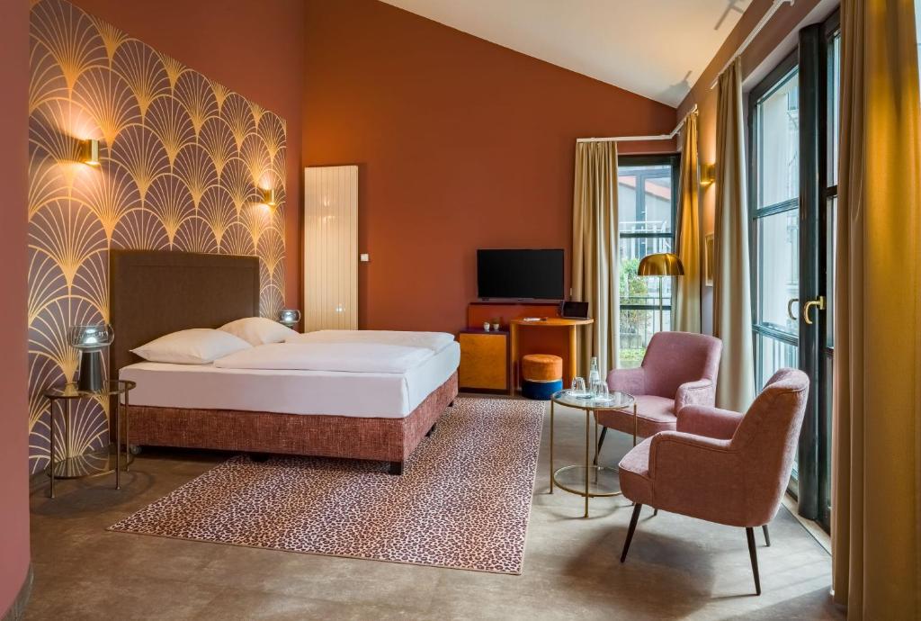 Ein Doppelzimmer mit Doppelbett und Sesseln im Hotel Domicil
