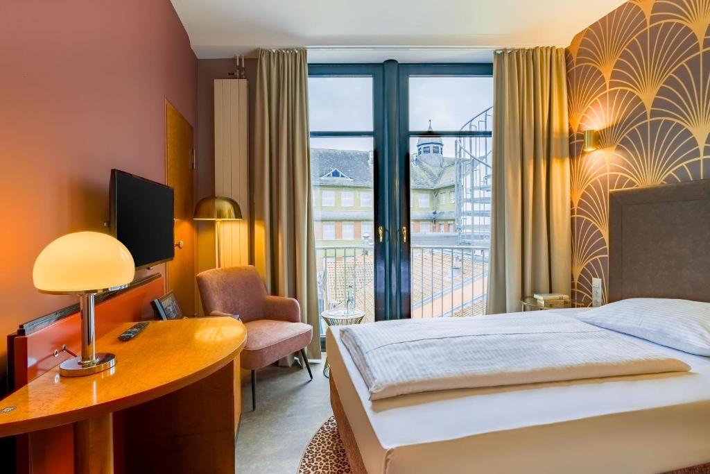 Ein Einzelzimmer mit Bett und Schreibtisch im Hotel Domicil