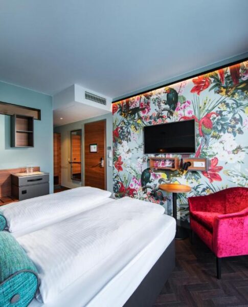 Das Bett und der Sessel eines Zimmers im Maison Schiller