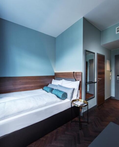 Das Doppelbett und der Spiegel eines Zimmers im Maison Schiller