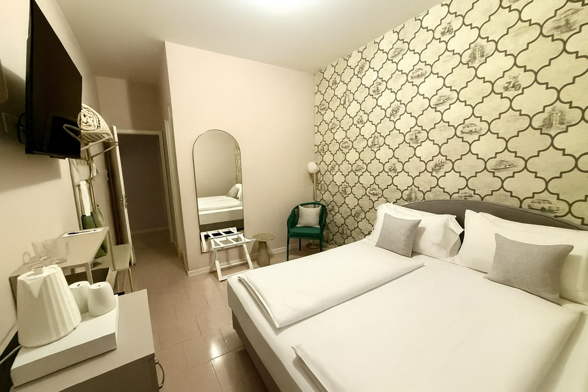 Ein Doppelzimmer mit Doppelbett, Schreibtisch und Spiegel im Hotel MioMio