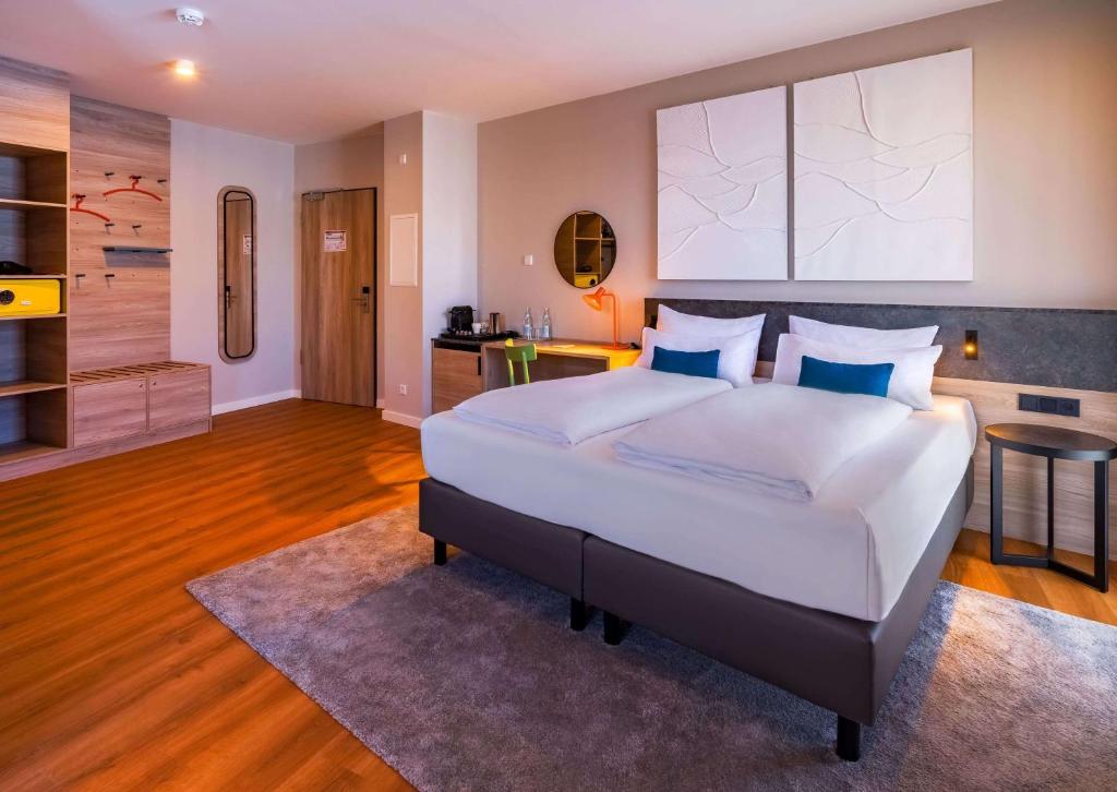 Das Doppelzimmer mit Doppelbett, Nachttischen und Kaffeemaschine im Ramada Encore by Wyndham Munich Messe