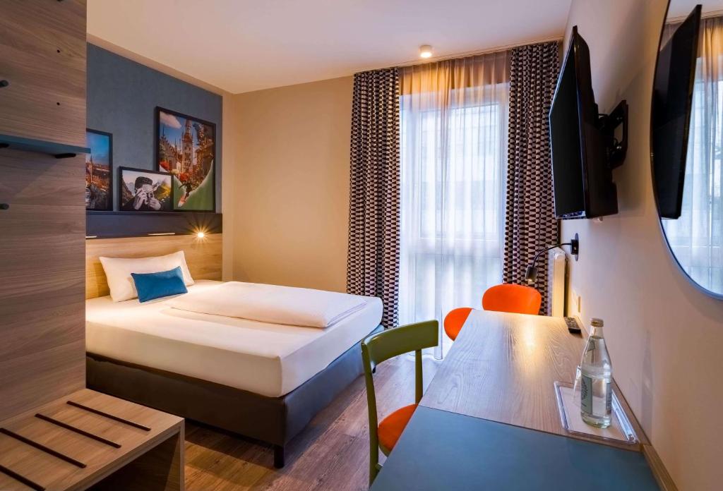 Ein Einzelzimmer mit Schreibtisch und Bett im Ramada Encore by Wyndham Munich Messe