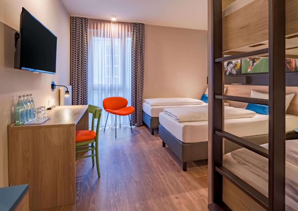 Das Vierbettzimmer mit Betten und Fernseher im Ramada Encore by Wyndham Munich Messe
