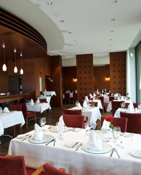 Der Speisesaal mit Tischen im rugs Hotel am Schlosspark Lichtenwalde