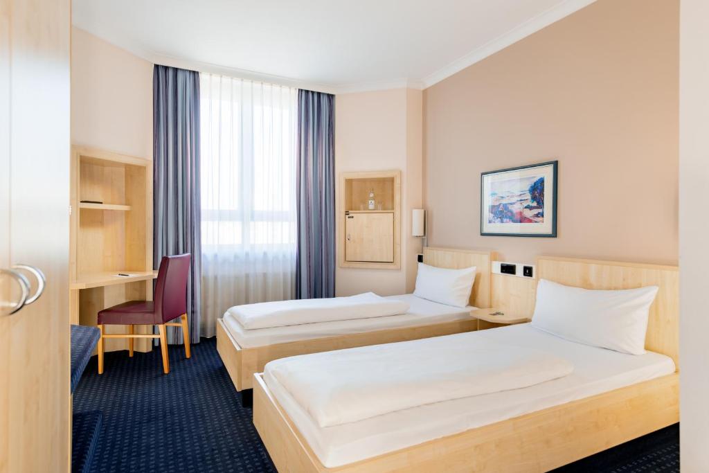 Ein Twin-Zimmer mit Schreibtisch und Einzelbetten im rugs Hotel Augsburg