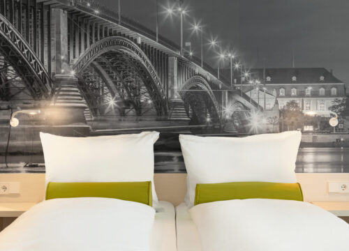 Das Doppelbett und die Nachttische eines Zimmers im Super8 by Wyndham Mainz Zollhafen