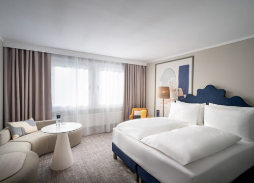 Ein Zimmer mit Doppelbett, Sessel und Sofa im voco Vienna Prater