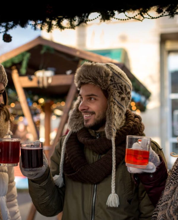 Junge Menschen trinken Glühwein auf einem Weihnachtsmarkt
