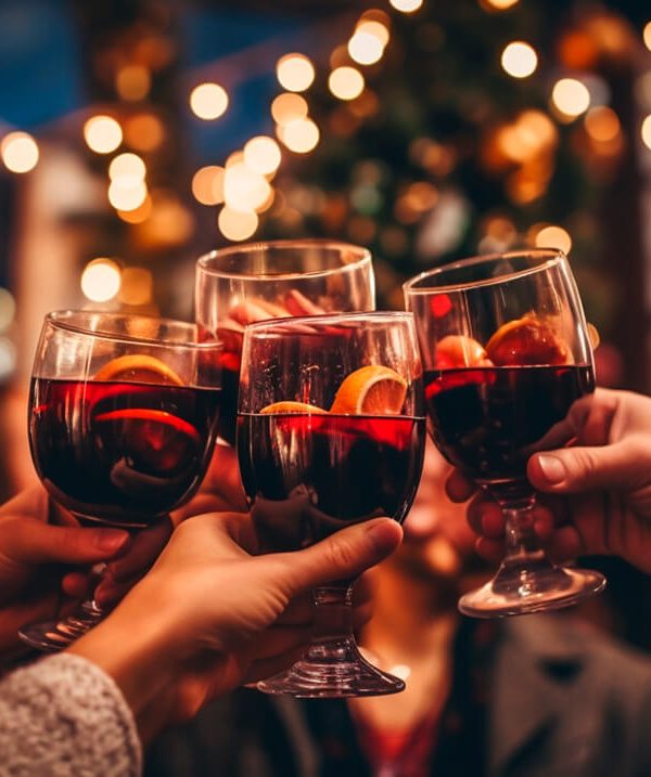 Besucher eines Weihnachtsmarktes stoßen mit Glühwein an